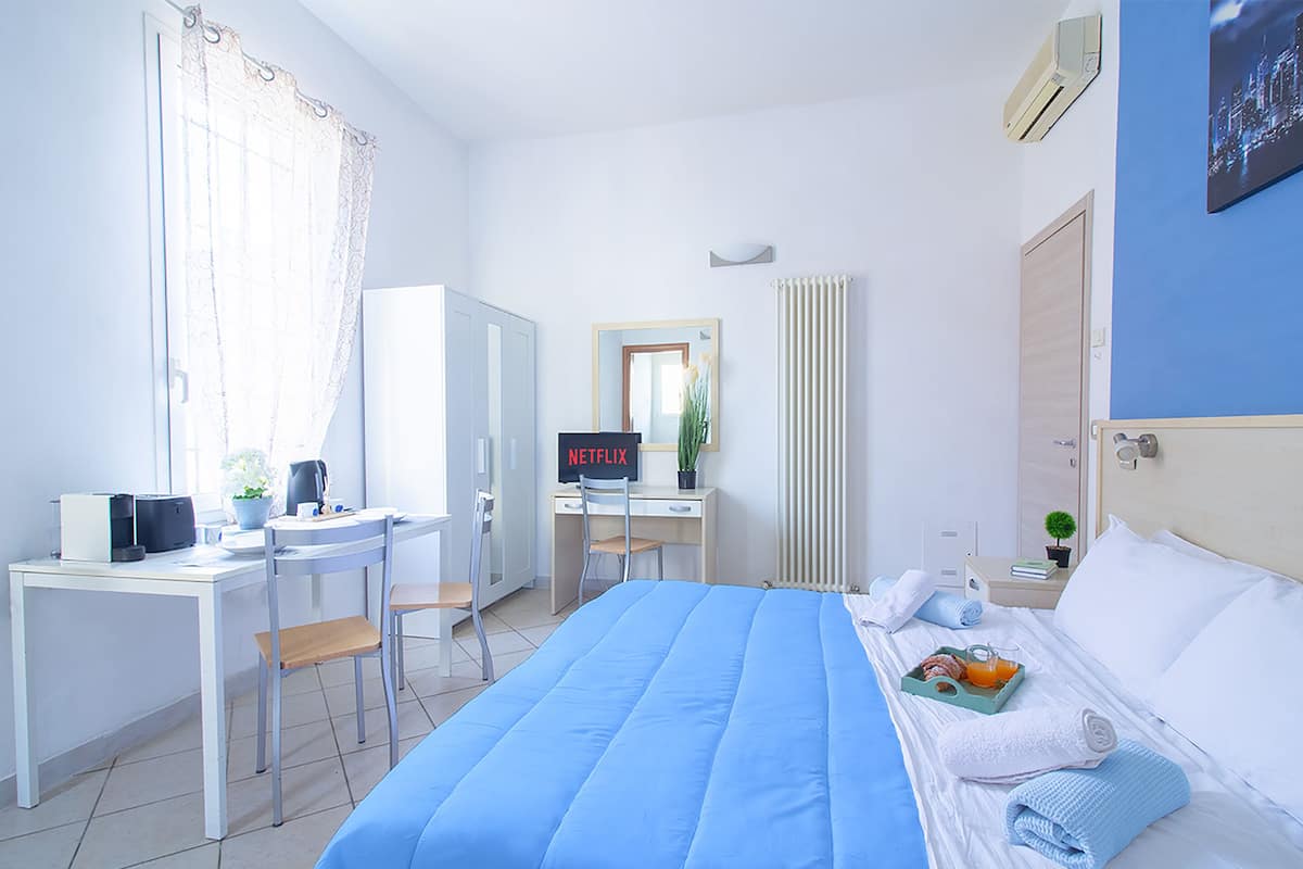 Ein Hotelzimmer mit Bett, Schreibtisch, Stuhl und einem Fernseher, der 'NETFLIX' anzeigt.