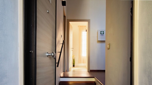 A staircase leading to a room with a wooden floor and a door with a metal frame. - Athena Affittacamere (Bologna)