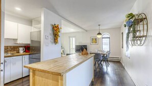 A modern kitchen with white cabinets, a wooden island, and a dining area with a table and chairs. - Le Plateau Boutique Apart Hotel (Montreal)