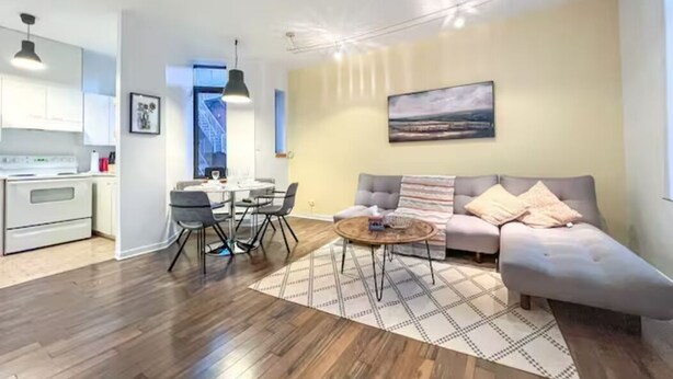 A modern living room with a sofa, coffee table, and dining area. - Le Plateau Boutique Apart Hotel (Montreal)