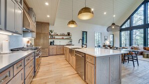 Een ruime keuken met houten kastjes, een centraal eiland en hanglampen.