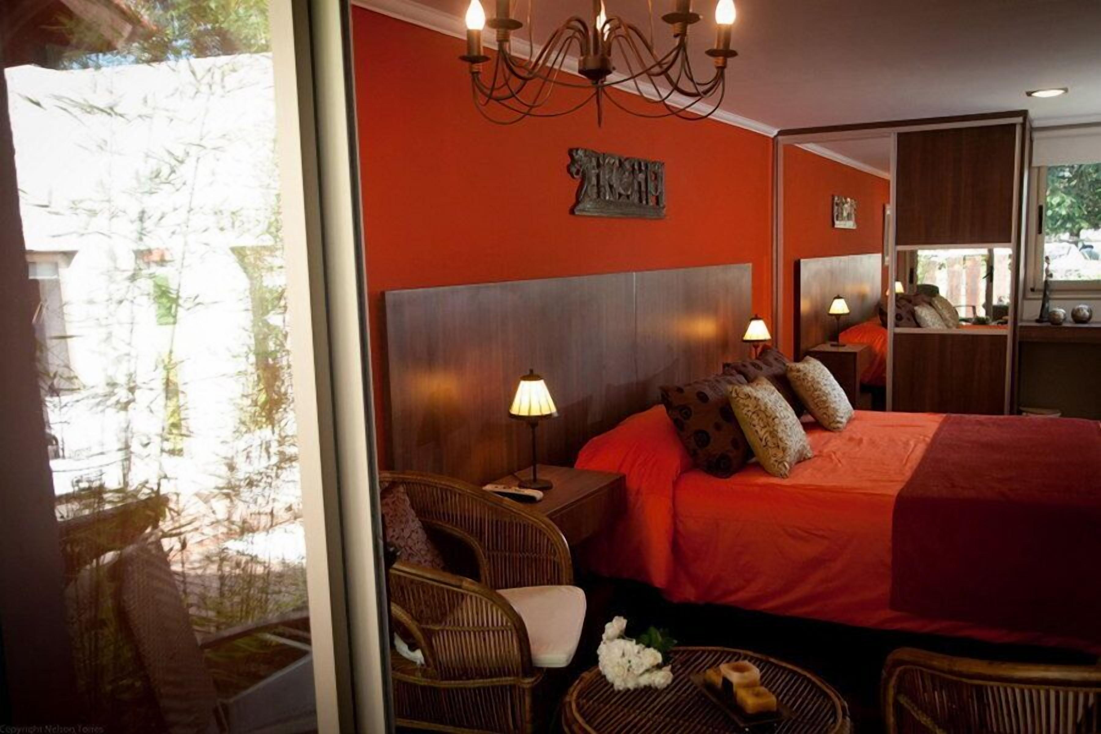 Ein Schlafzimmer mit einem großen Bett, zwei Nachttischlampen, einem Kronleuchter und Korbmöbeln.
