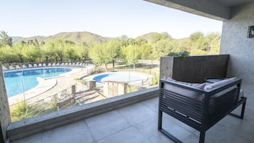 En balkong med pool, utomhusmöbler och utsikt över bergen.