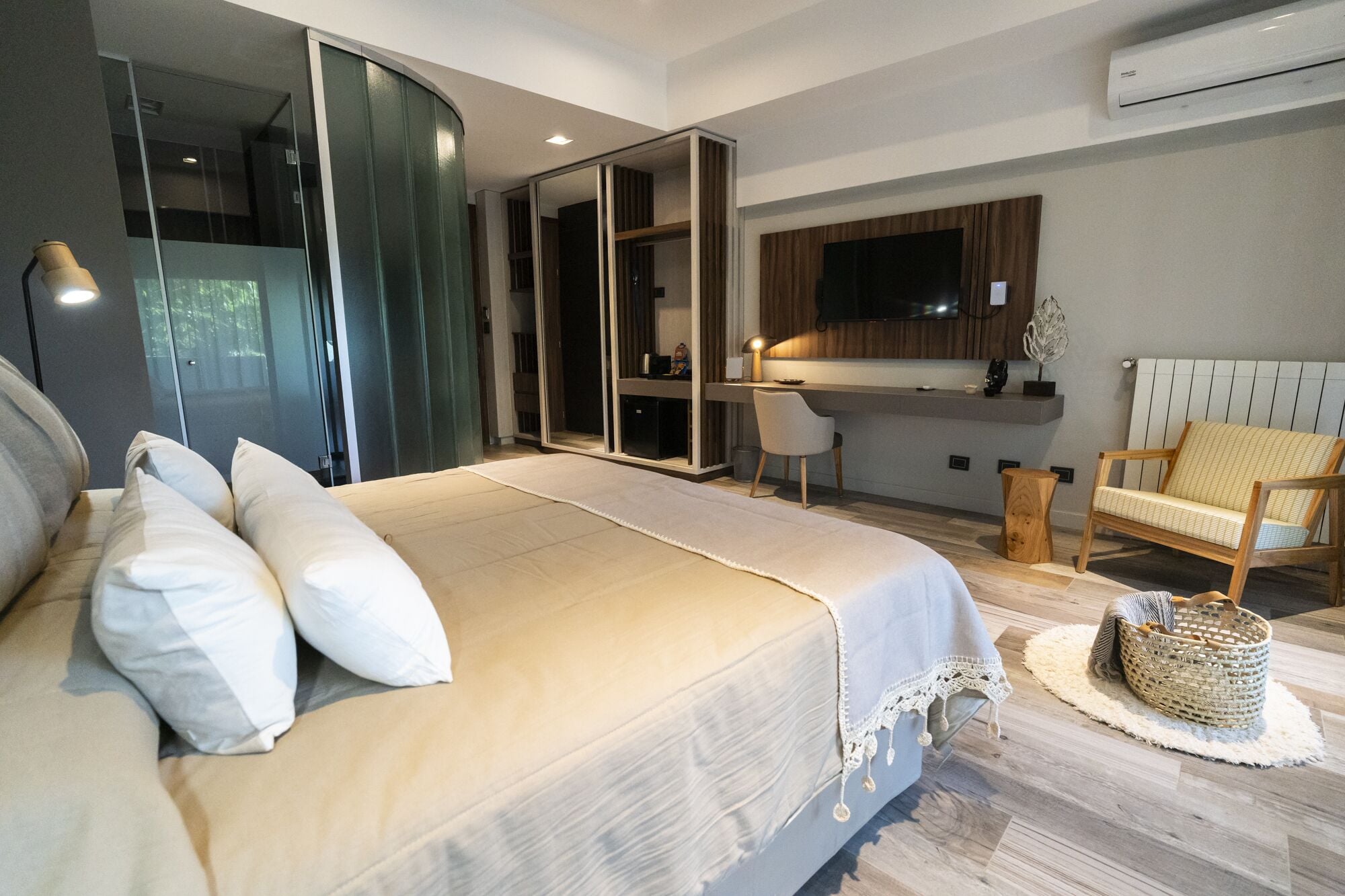 Un dormitorio moderno con una cama grande, un escritorio y un televisor montado en la pared.
