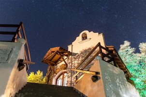 Una vista nocturna de un edificio con una escalera que lleva a una torre, bajo un cielo estrellado.