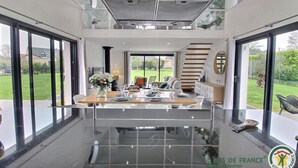 A modern kitchen with a central island, large windows, and a view of the outdoors. - Les Herbes Folles - Tregastel (TREGASTEL)