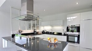 Una cocina moderna con una isla central, electrodomésticos de acero inoxidable y armarios blancos.