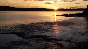 Ein Sonnenuntergang über einem stillen See mit steiniger Uferlinie.
