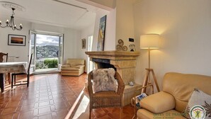 Ein gemütliches Wohnzimmer mit Kamin, einer Couch, einem Sessel und einem Esstisch.