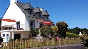 Ein zweistöckiges Haus mit weißer Fassade, dunklem Dach und Holzzaun.