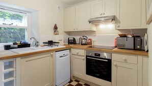 Uma cozinha com armários brancos, lava-louças, forno, micro-ondas e torradeira.
