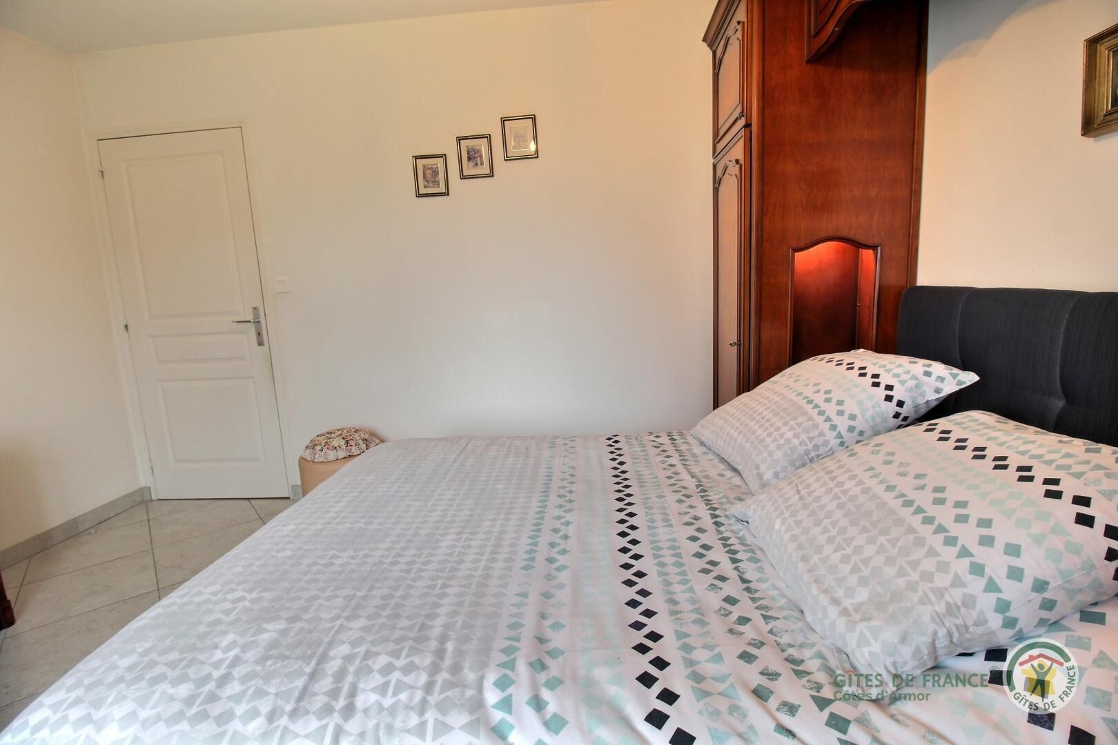 A bedroom with a bed, a wooden wardrobe, and a door.