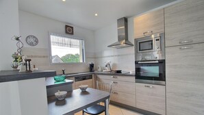 Una cocina moderna con horno empotrado, microondas y lavavajillas. Hay una ventana que ofrece vistas a zonas verdes.