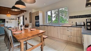 Una cocina moderna con armarios de madera, un ventanal grande e iluminación colgante.