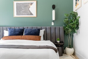 A bedroom with a bed, pillows, a bedside table, a wall-mounted light, and a potted plant. - 4BR Branson Holidays | Hot Tub · Slides · Pool (Hollister)
