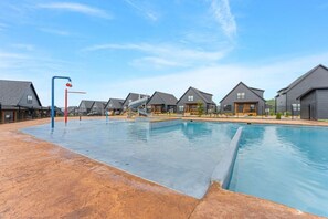 A swimming pool area with a slide, surrounded by houses with dark roofs.