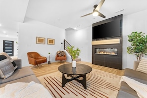 A modern living room with a fireplace, leather sofas, a coffee table, and a ceiling fan.