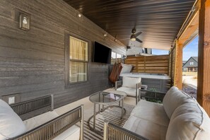 Et overdækket udendørs opholdsområde med sofa, stole, bord og jacuzzi.