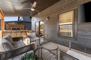 An outdoor patio area with a grill, seating, and a view of the surrounding area.