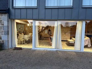 En bygning med store skydedøre, der fører til et spiseområde indeni med et bord og stole.