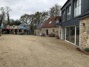 Landlig omgivelser med en grusindkørsel, stenvægge og en træbygning med rødt tag.