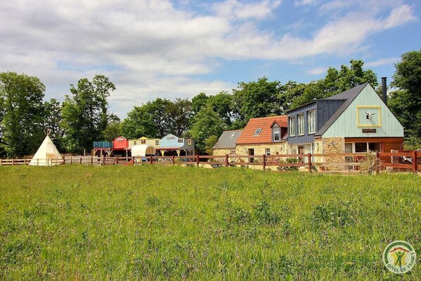 Et landligt område med forskellige bygninger, heriblandt et stort hus med saddeltag og en mindre bygning med rødt tag.