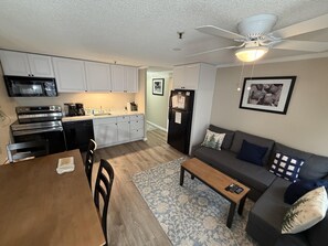 A compact living space with a kitchenette, a dining area, and a seating area with a sofa and a coffee table. - ML 359: Comfy & cozy bike-in/out summer retreat! (Snowshoe)
