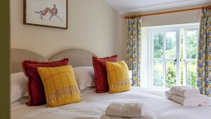 Una habitación de hotel con cama, almohadas, un cuadro enmarco y una ventana con cortinas.