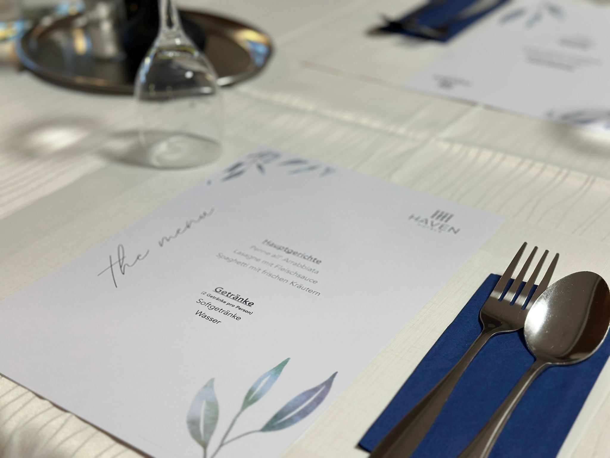 A menu card with a list of dishes and a fork and spoon set on a table.