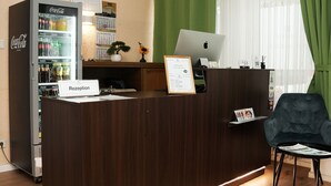 Uma mesa de recepção com um refrigerador de Coca-Cola, um laptop e um letreiro de boas-vindas emoldurado.