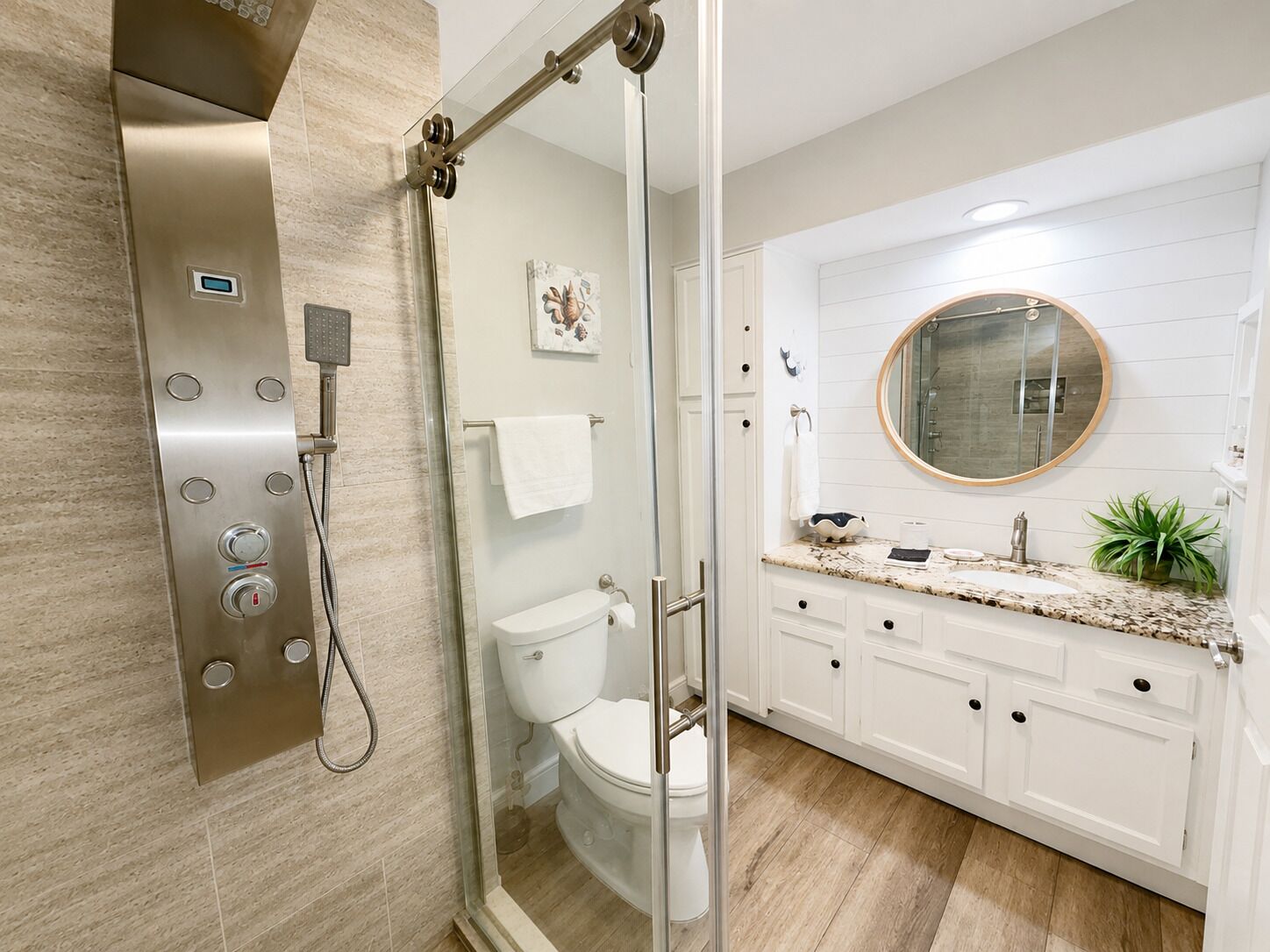 A modern bathroom with a glass-enclosed shower, a toilet, a sink with a mirror, and a plant.