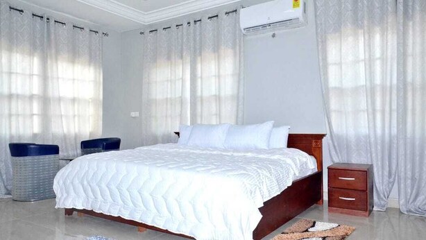 A bedroom with a bed, a nightstand, a trash bin, and a ceiling fan. - Tamarind Guesthouse (Aburi)
