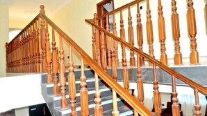 A wooden staircase with a handrail and balusters, leading to an upper floor. - Tamarind Guesthouse (Aburi)