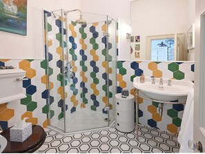 Un baño con cabina de ducha de vidrio, un lavabo blanco y un inodoro.