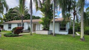 A single-story house with a sloped roof, surrounded by a well-maintained lawn and palm trees. - Private Apartment Miami Kendall near Zoo, The Falls Mall, and Miami Dade College (Miami)