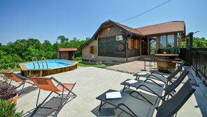 Une maison en bois avec une piscine, un espace salon extérieur et une grande table en forme de tonneau.