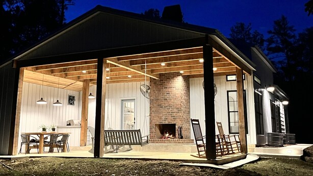 A covered outdoor area with a brick fireplace, wooden benches, and a dining table with chairs. - Secluded cottage nestled in the Homochitto National Forest. Fireplace & pond. (Crosby)