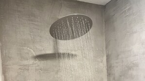 A showerhead with water flowing down a textured wall. - Secluded cottage nestled in the Homochitto National Forest. Fireplace & pond. (Crosby)