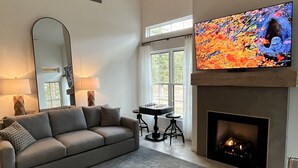 A living room with a gray sofa, a fireplace, a television, and a ceiling fan. - Secluded cottage nestled in the Homochitto National Forest. Fireplace & pond. (Crosby)