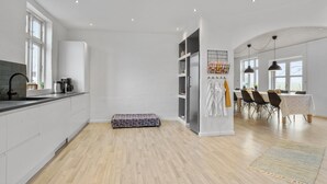 Una cocina moderna con horno empotrado, una zona de comedor con mesa y sillas, y un ventanal que proporciona luz natural.
