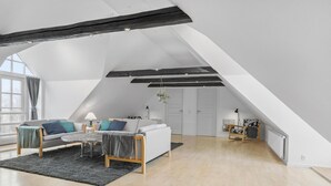 Un loft amplio con techos altos, vigas a la vista y un ventanal que proporciona luz natural.