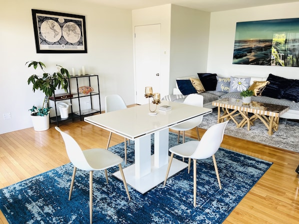 Ein modernes Wohnzimmer mit Essbereich, ausgestattet mit einer weißen Sofagarnitur, einem Couchtisch und einer großen Weltkarte an der Wand.
