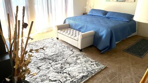 A bedroom with a bed, a small white chair, a rug, and a painting on the wall. - West Hollywood, Hollywood Hills, Sunset Strip House with Beautiful Views (Beverly Hills)