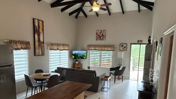 A spacious kitchen with a wooden bar, modern appliances, and a dining area with chairs and a table. - B’s Hidden Paradise (Mary’s Fancy)