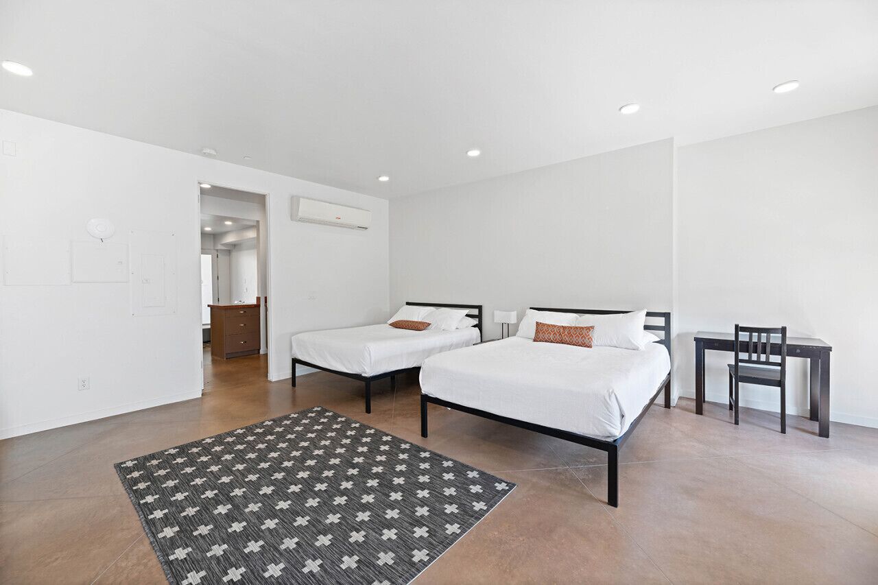 Une chambre d’hôtel moderne équipée de deux lits simples, d’un bureau et d’une chaise.