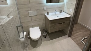 Een moderne badkamer met toilet, wastafel en spiegel.