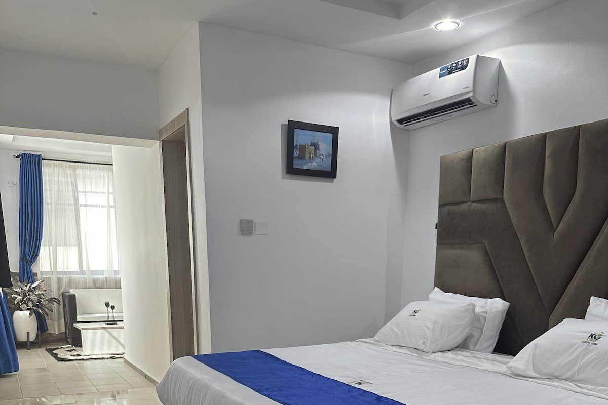 Un dormitorio moderno con una cama grande, un cabecero gris y una almohada decorativa azul.