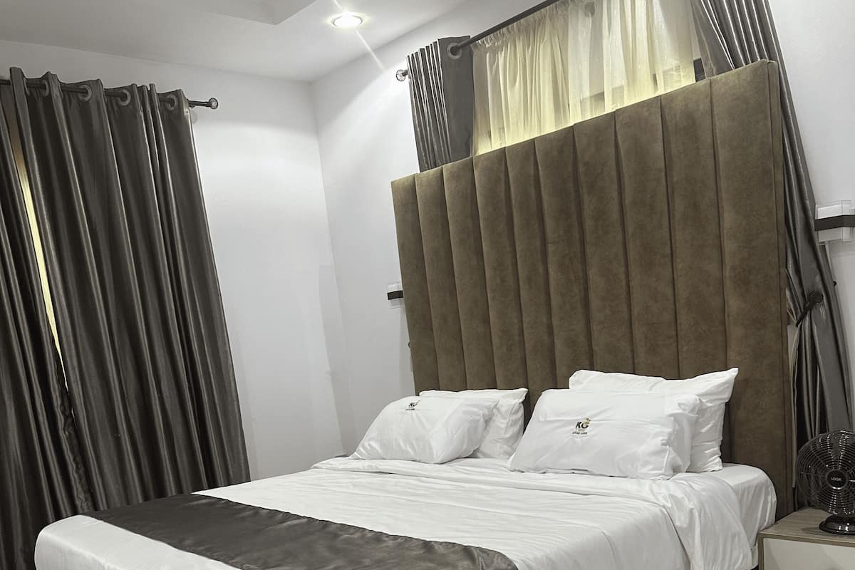 Un dormitorio moderno con una cama grande, una mesita de noche y un velador.