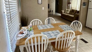 A dining area with a wooden table, white chairs, and a ceiling fan.