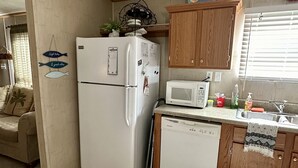 A compact kitchen with a refrigerator, microwave, and wooden cabinets.